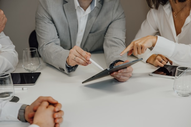 a group of people sitting around a table with a pair of scissors