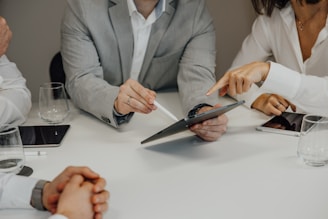a group of people sitting around a table with a pair of scissors