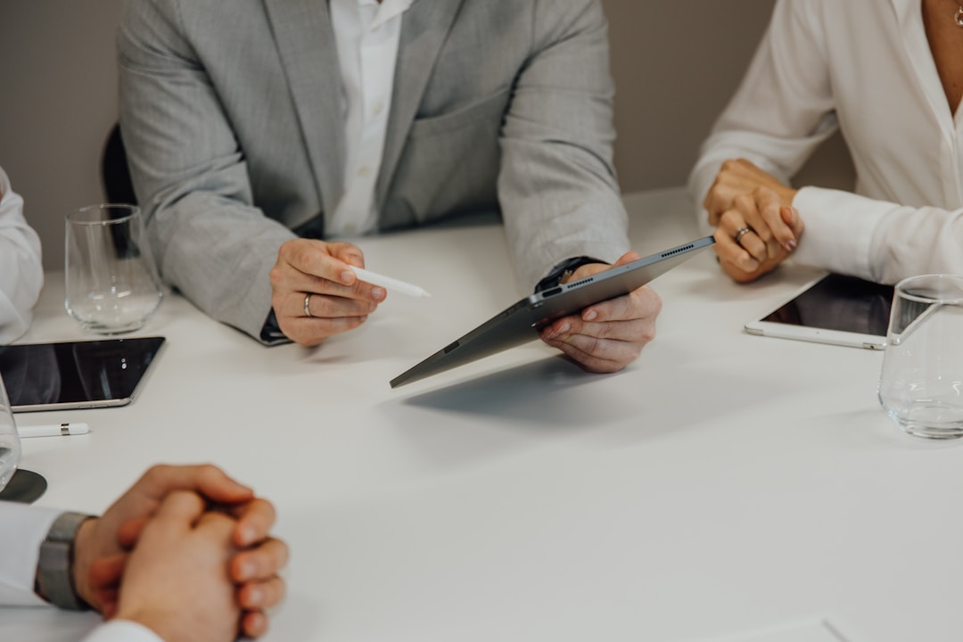 Business professionals at a table, focused on their laptops, discussing the importance of customer segmentation.