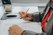 a person sitting at a desk writing on a piece of paper