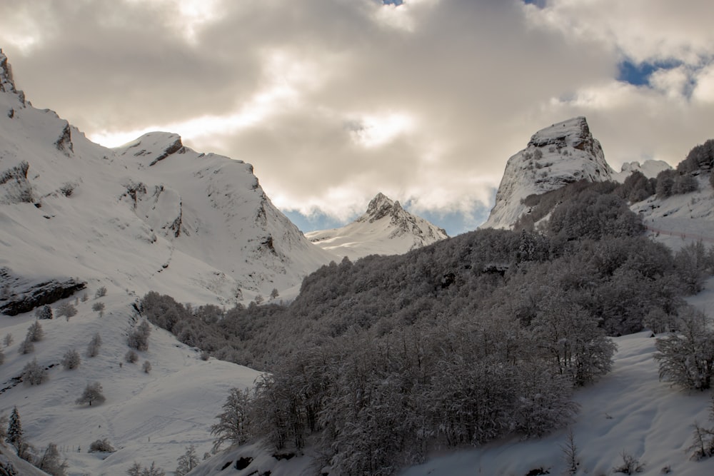 a snow covered mountain with trees and clouds