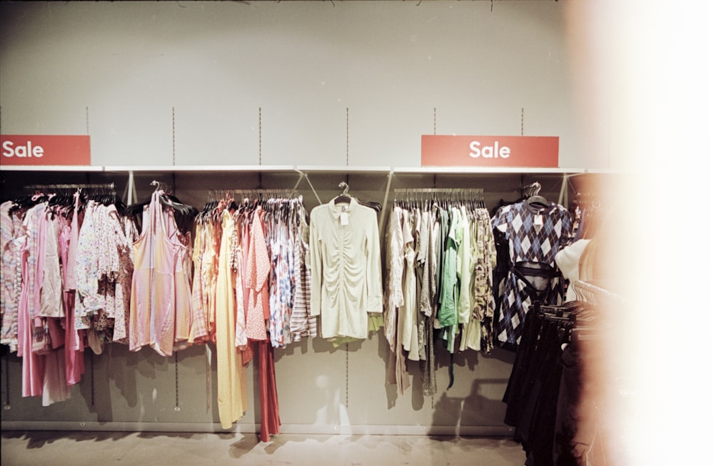 a rack of clothes with a sale sign in the background
