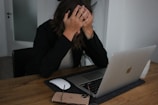 a woman covering her face while looking at a laptop
