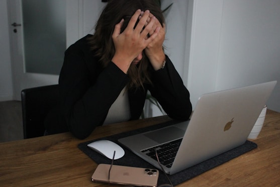 a woman covering her face while looking at a laptop