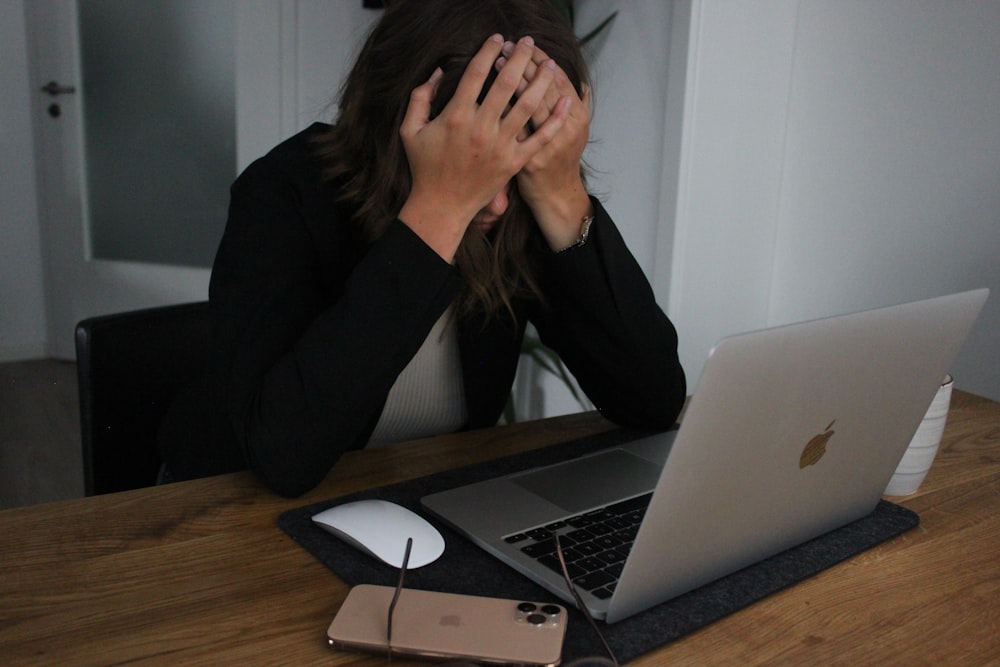 a woman covering her face while looking at a laptop