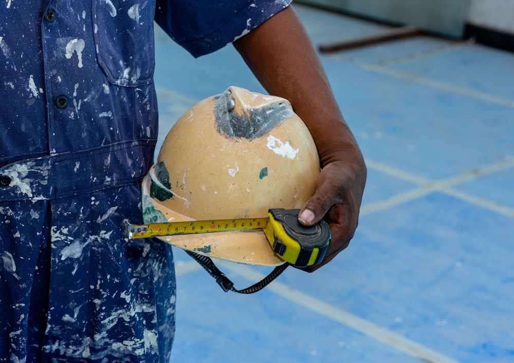 a man holding a hard hat and a measuring tape