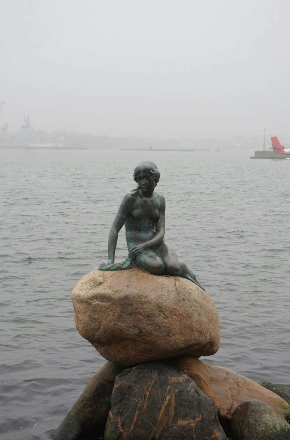 a statue of a little girl sitting on top of a rock