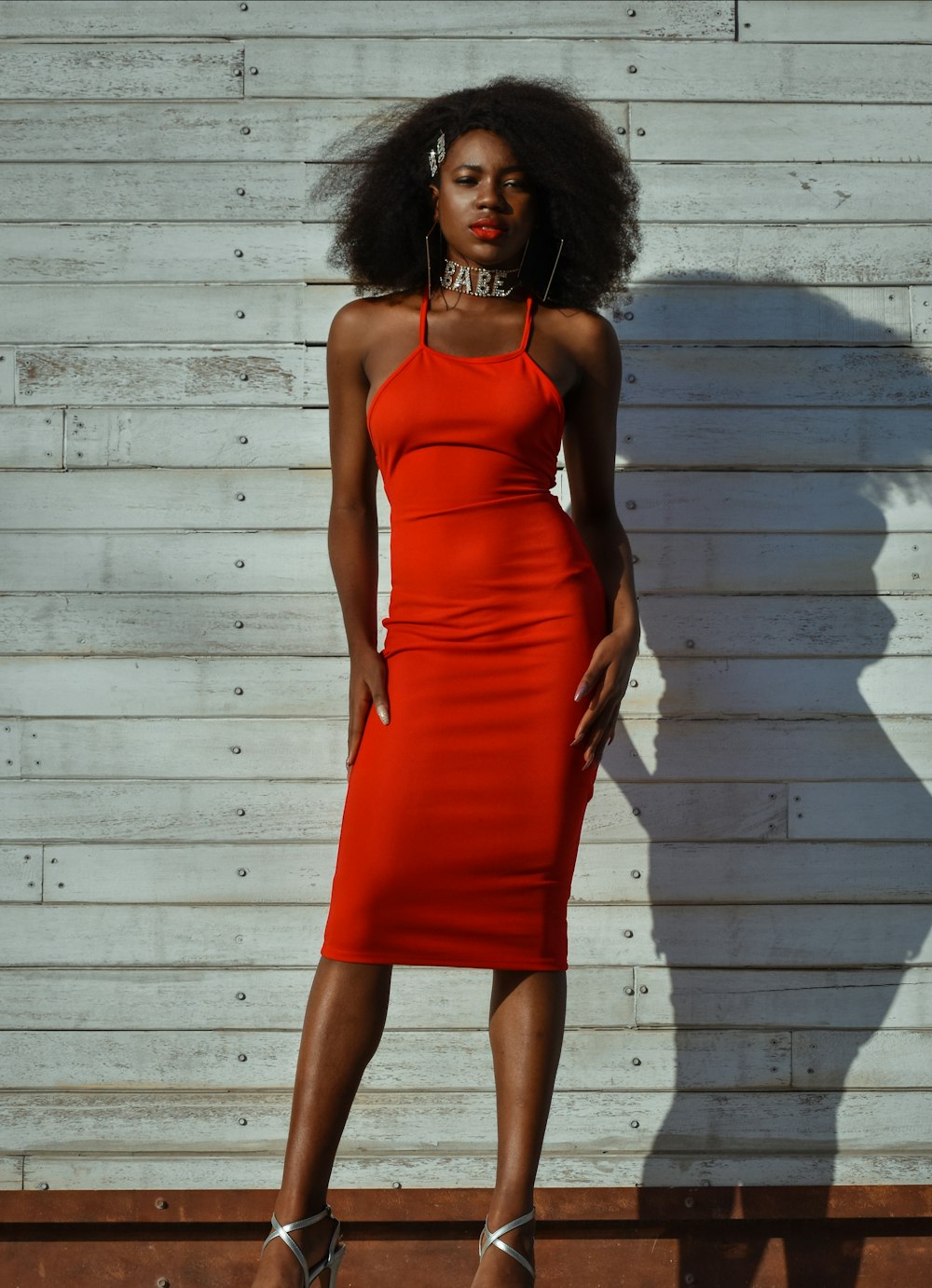 a woman in an orange dress standing in front of a white wall
