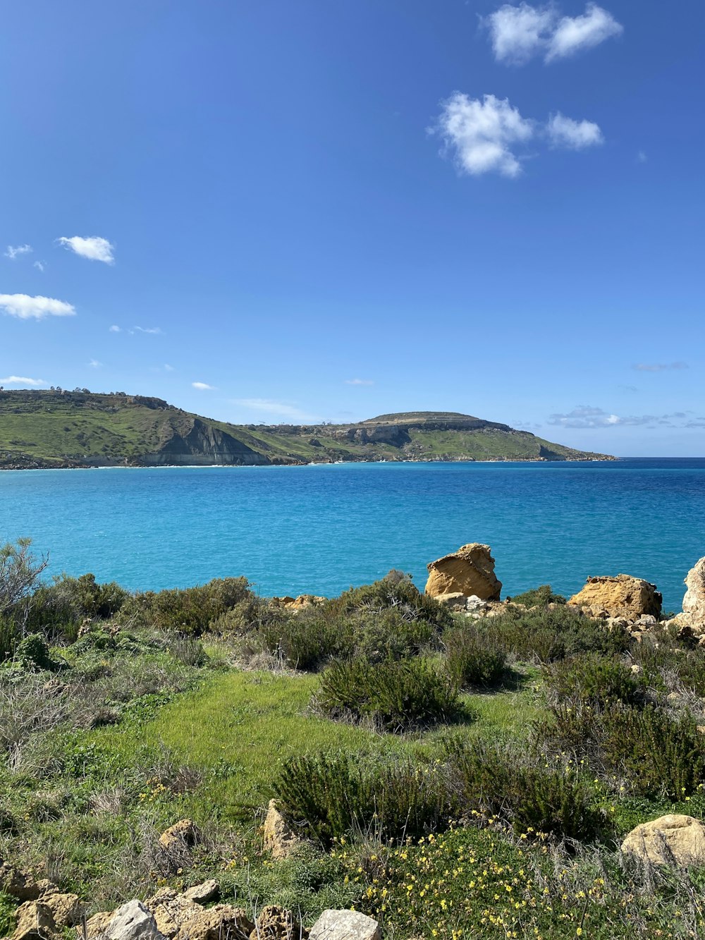 a large body of water sitting next to a lush green hillside