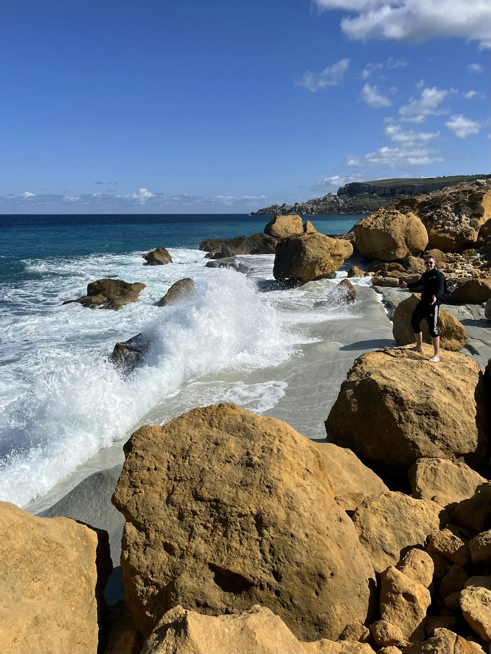 a man standing on a rocky beach next to the ocean