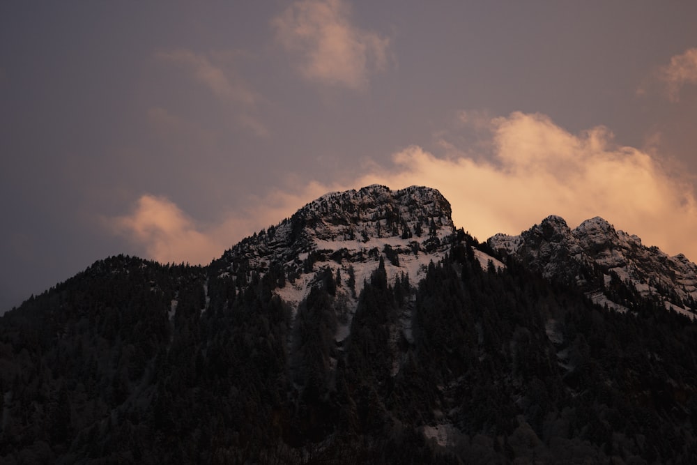 the top of a snow covered mountain under a cloudy sky