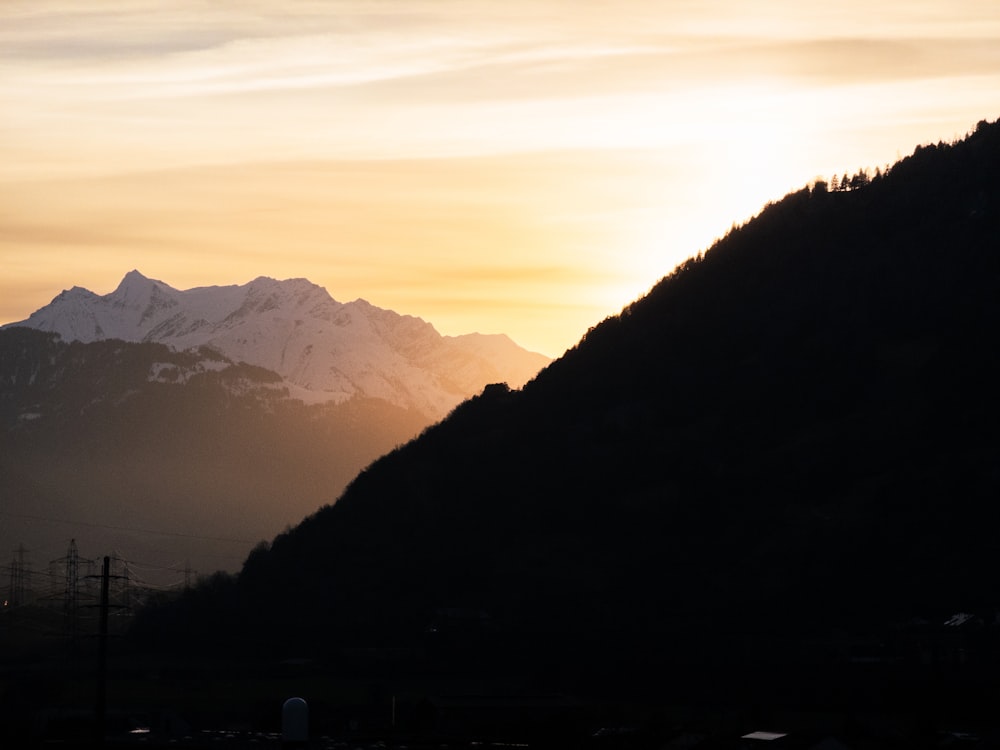 the sun is setting behind a mountain range