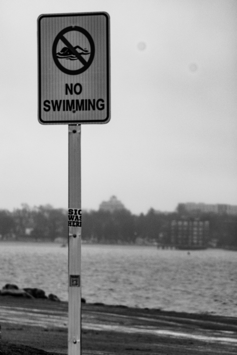 a black and white photo of a no swimming sign