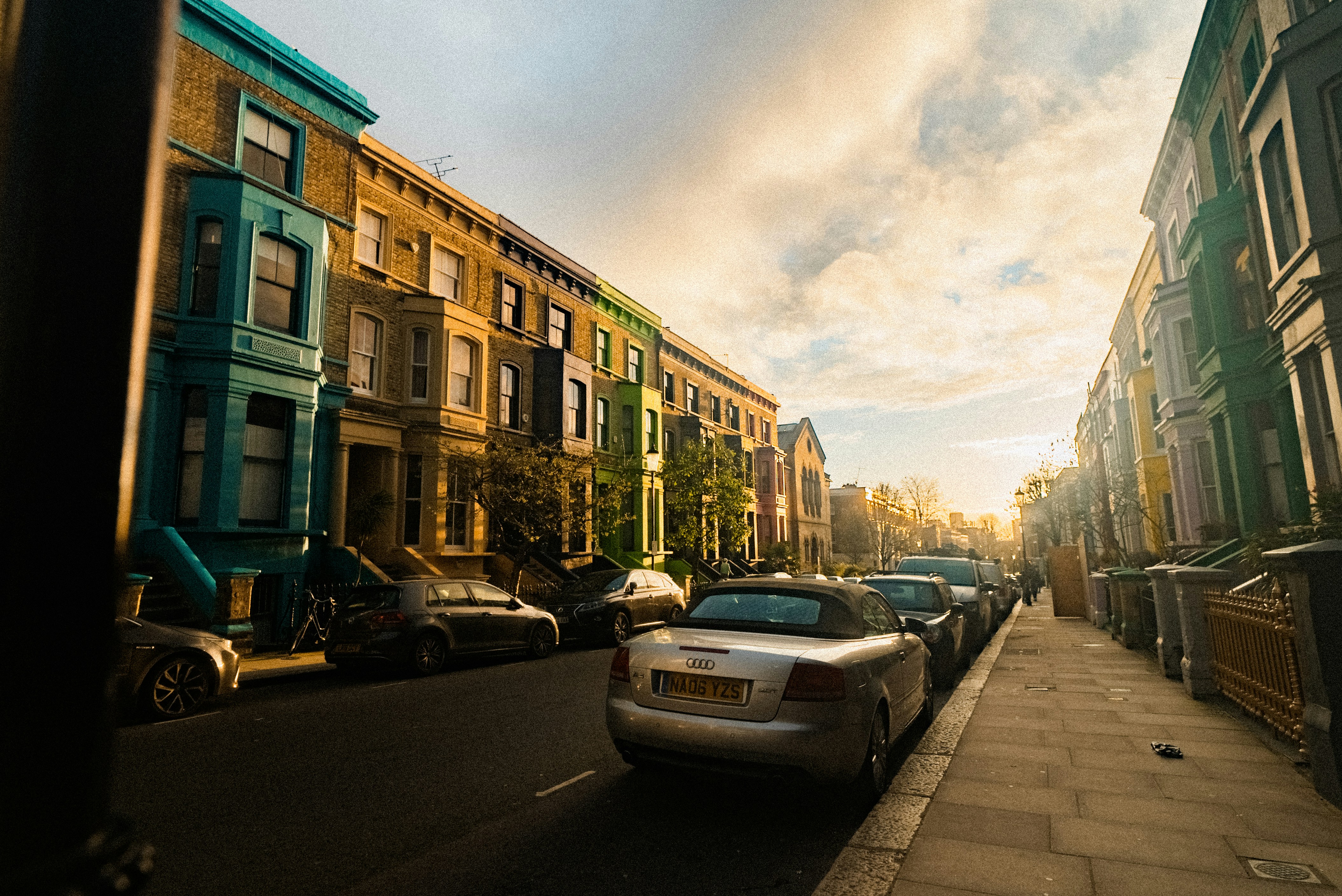 A city street filled with parked cars next to tall buildings photo ...