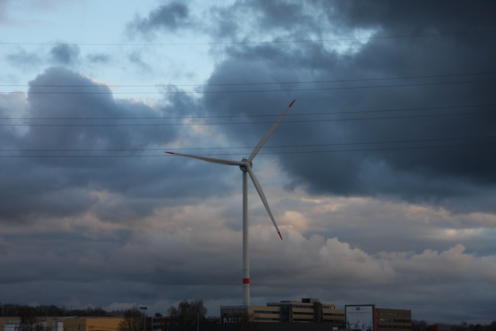 a wind turbine on a cloudy day with power lines in the background