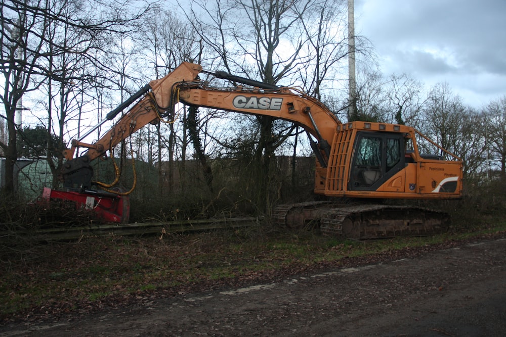 a large orange excavator sitting on the side of a road