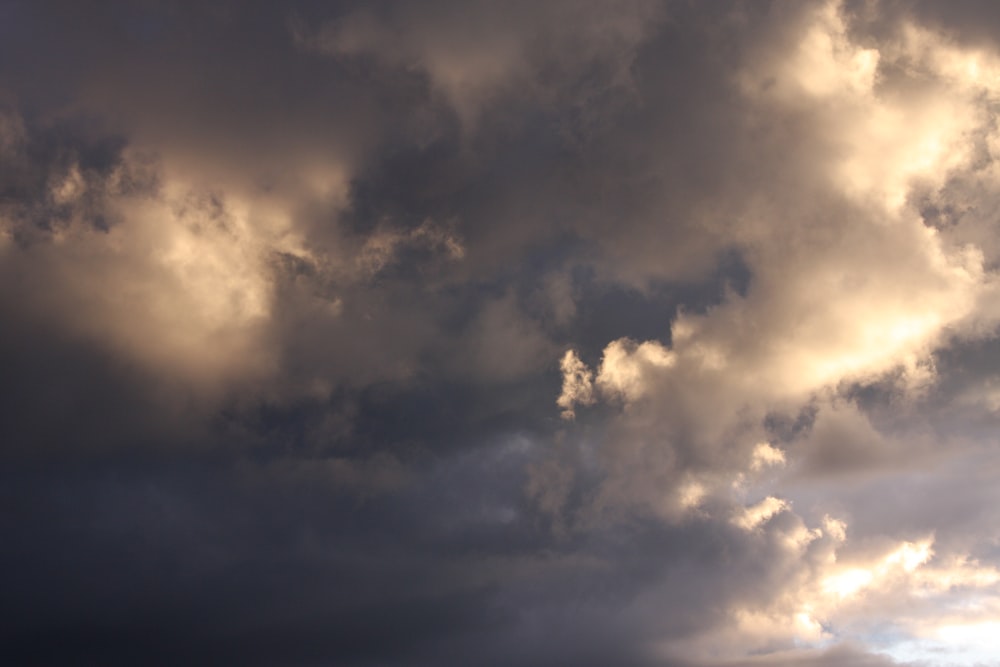 a plane flying through a cloudy sky on a sunny day