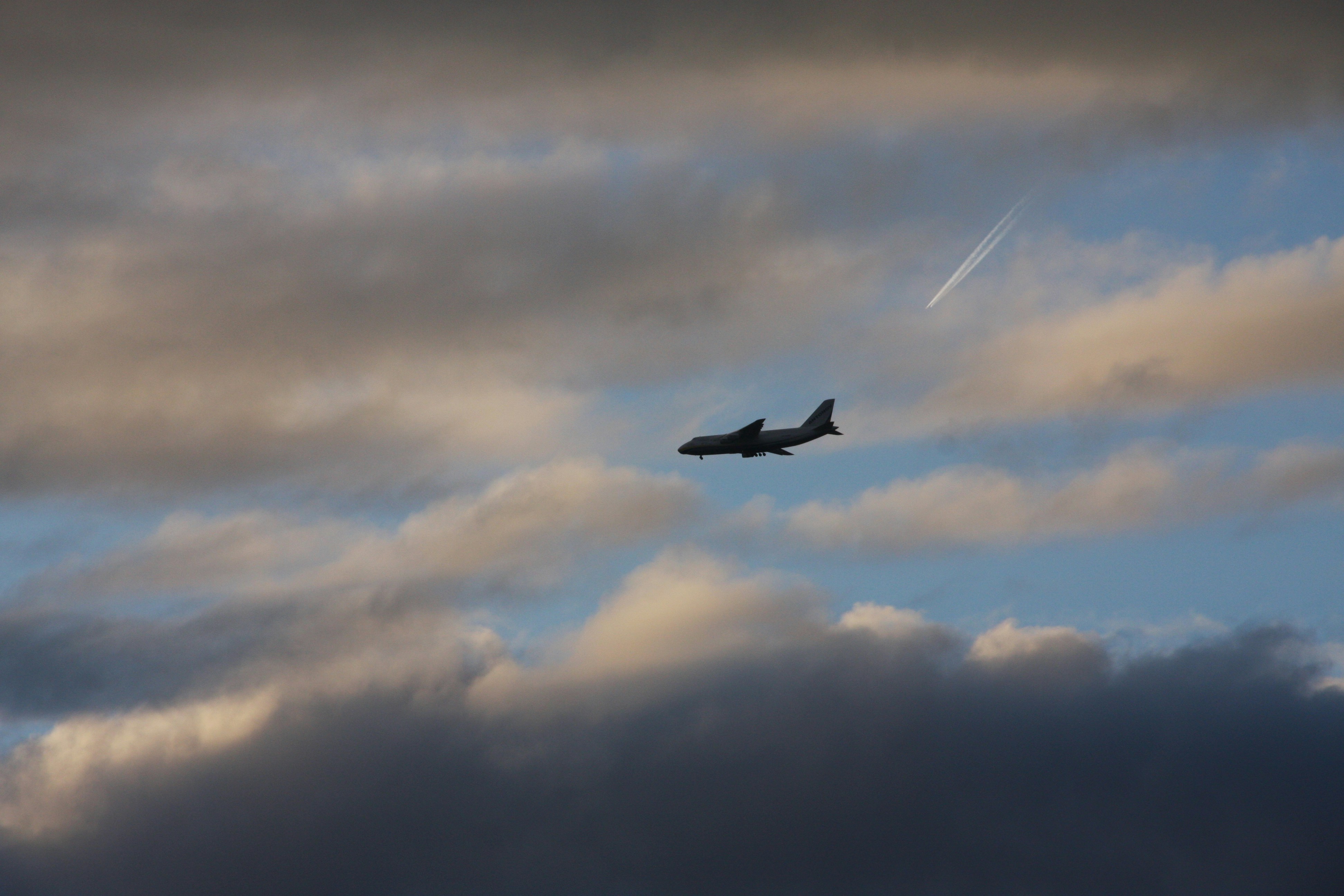 a plane flying through a cloudy blue sky, Avion Antonov sous un ciel gris, bleuté et orangé.