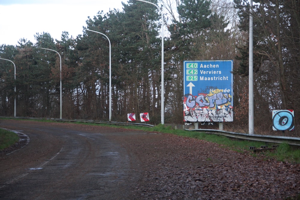 a sign on the side of a road with trees in the background