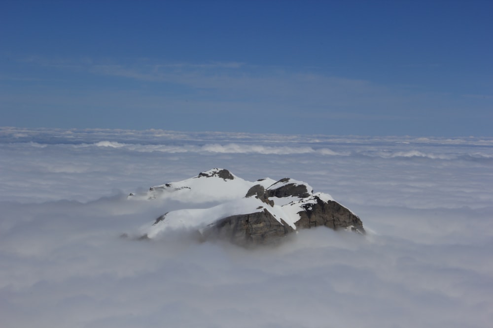 a mountain covered in snow surrounded by clouds