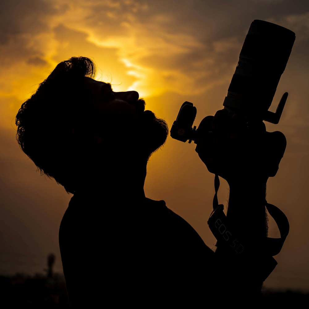 a silhouette of a person holding a camera