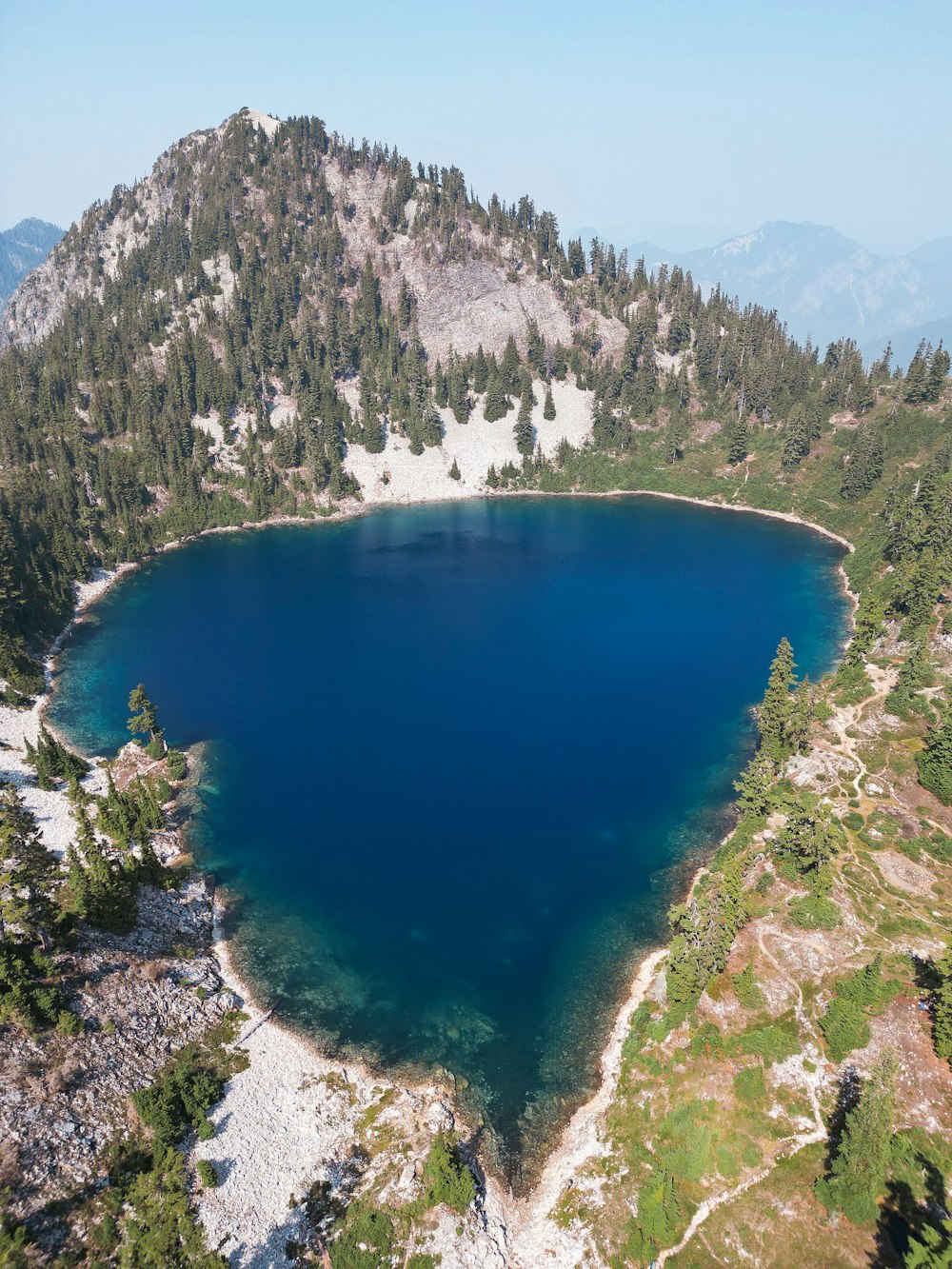 um grande lago azul cercado por montanhas e árvores