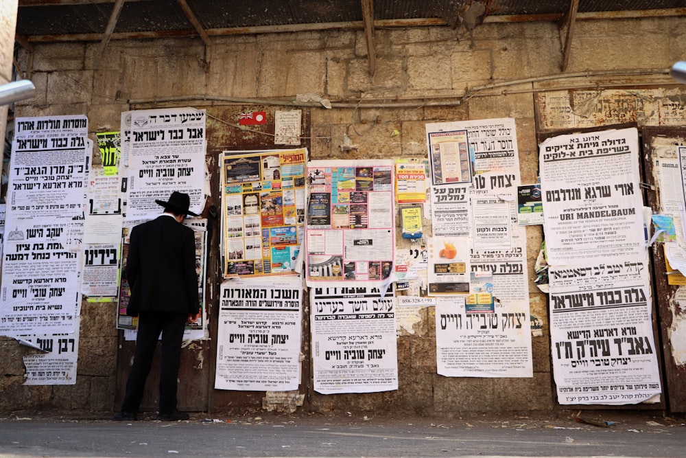a man standing in front of a wall covered in newspapers