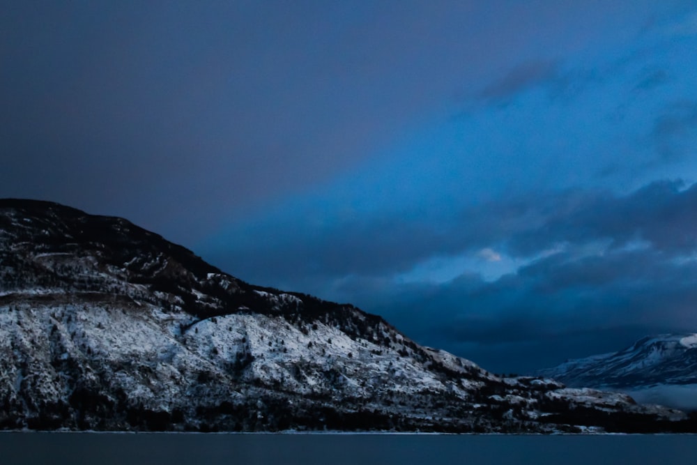 a mountain with snow on it and a body of water in front of it