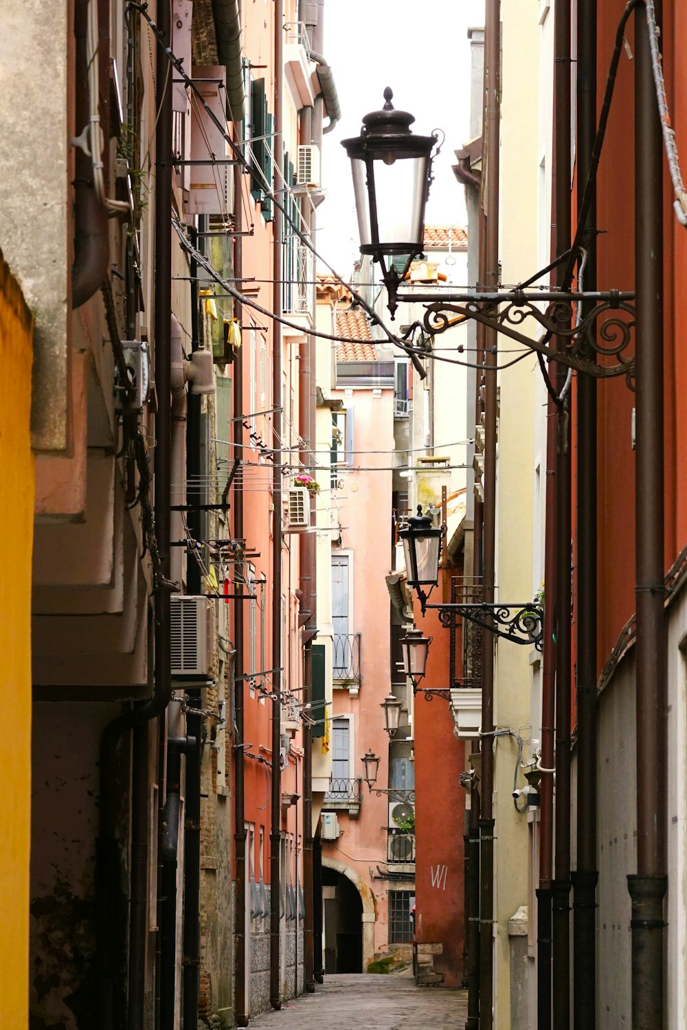 a narrow alley way with a lamp post in the middle