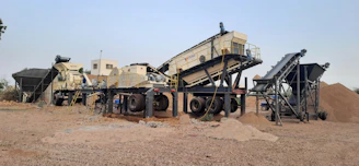 a group of cement mixers sitting on top of a dirt field