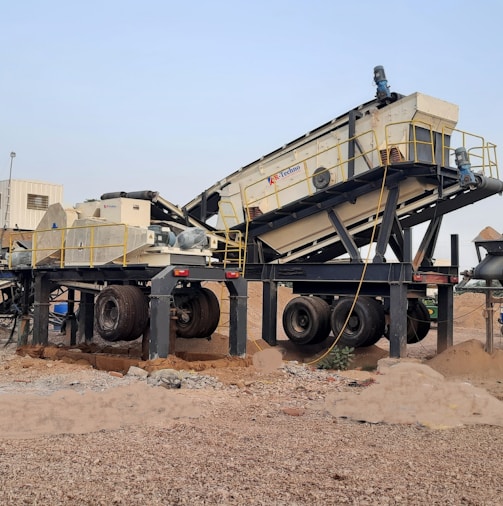 a group of cement mixers sitting on top of a dirt field