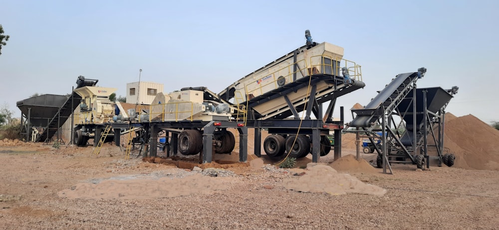 a group of cement mixers sitting on top of a dirt field