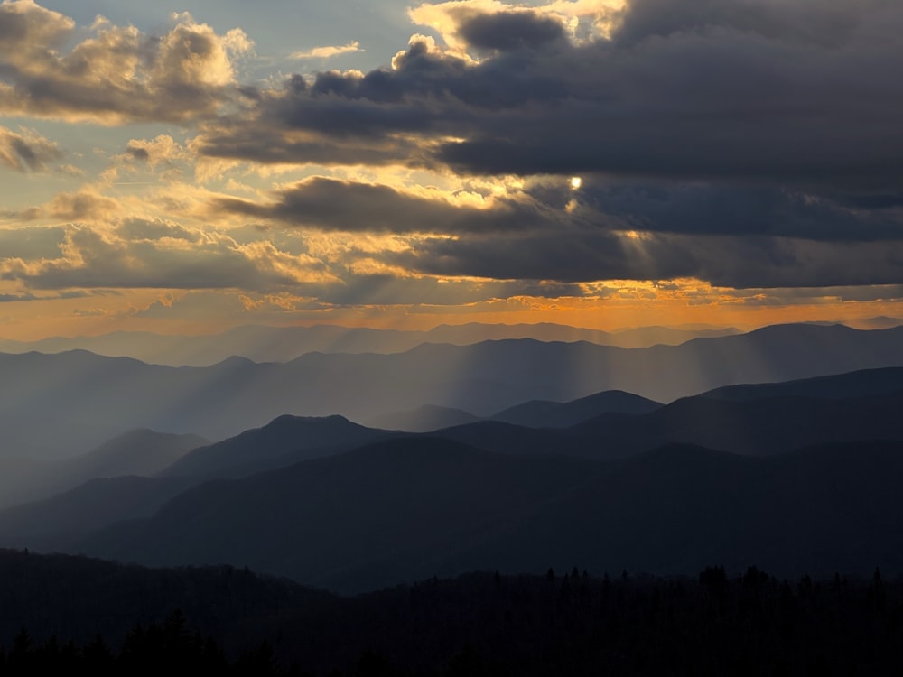 the sun is shining through the clouds over the mountains