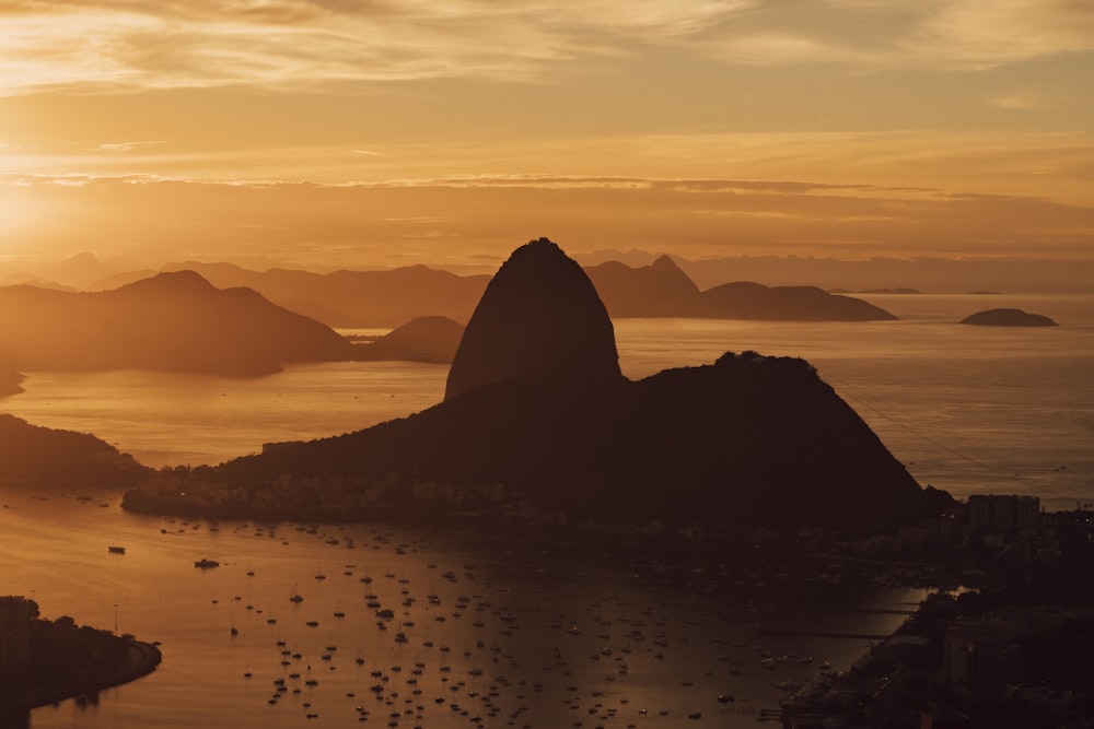 um pôr do sol sobre um corpo de água com montanhas ao fundo