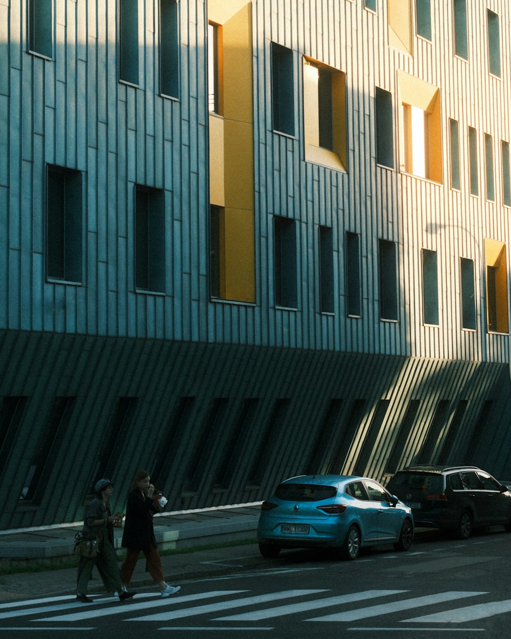 a woman walking down a street next to a tall building