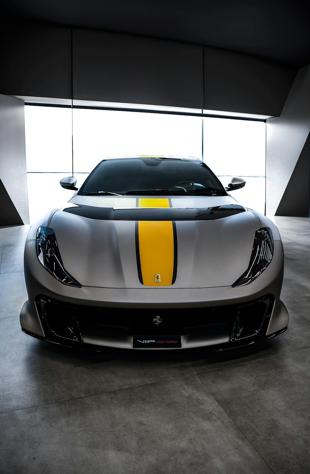 a silver sports car with yellow stripes parked in a garage