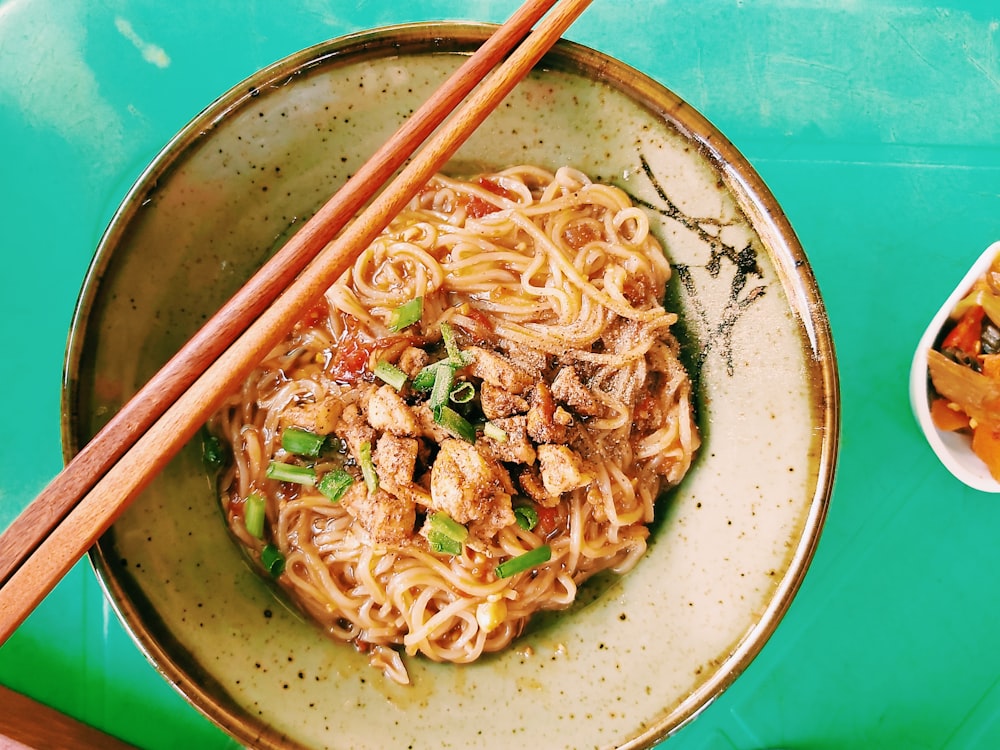 a bowl of noodles and chopsticks on a table