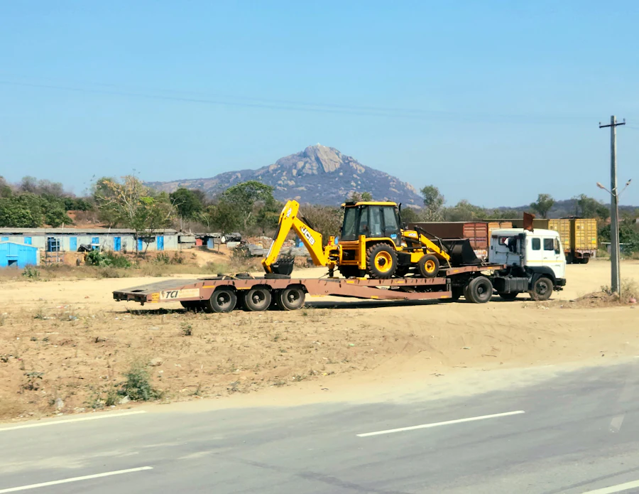 Flatbed trailer hauling strapped construction equipment