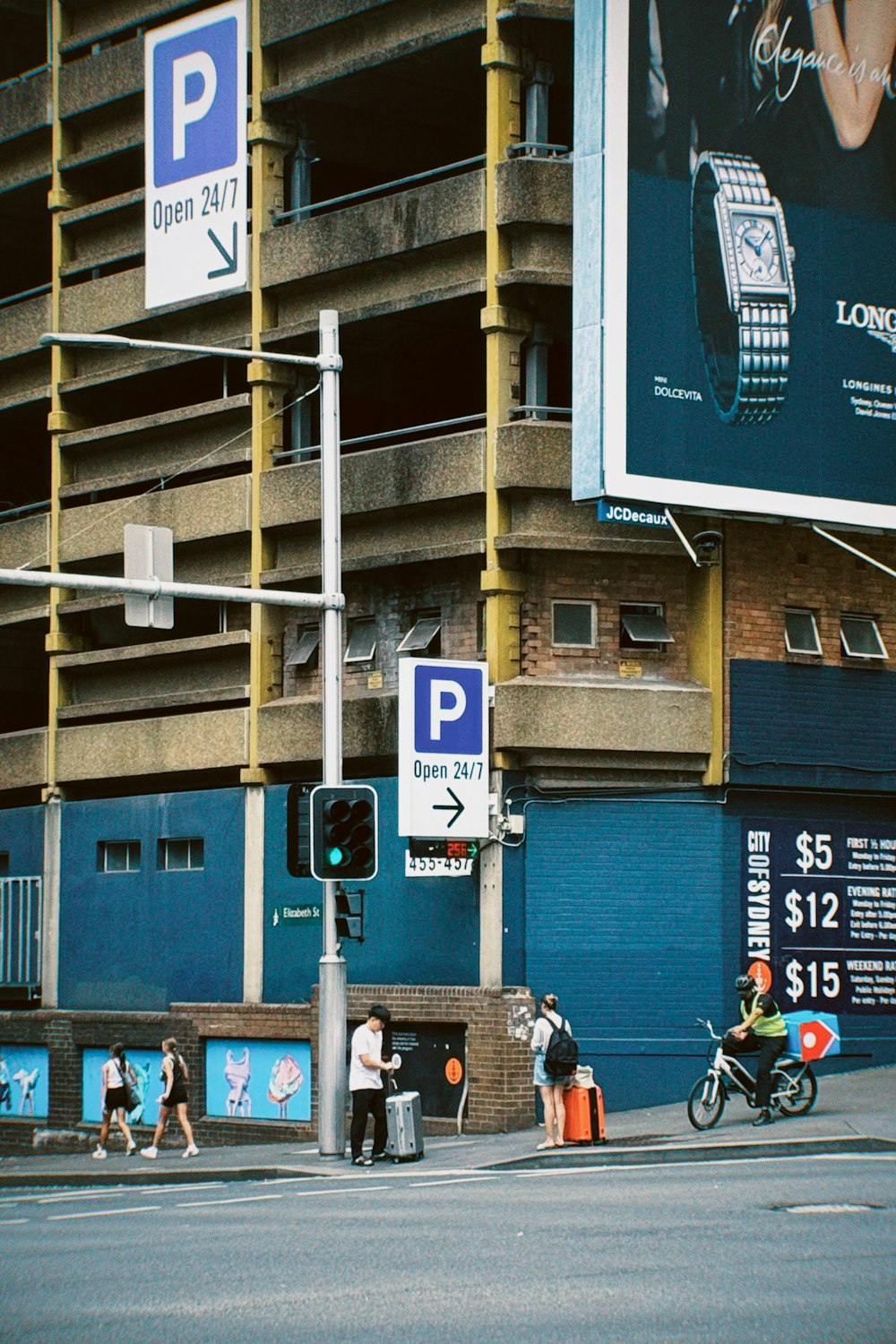 a man riding a motorcycle down a street next to a tall building