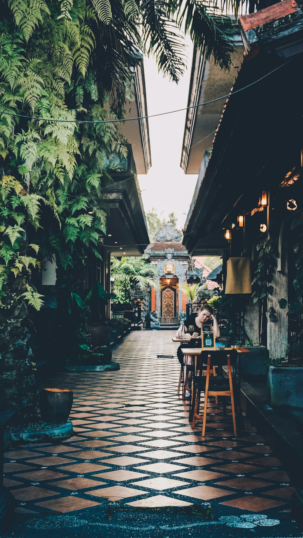 a person sitting at a table in a courtyard