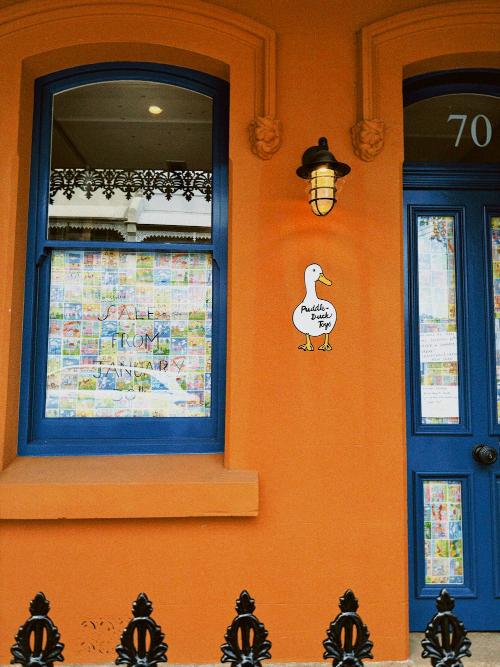 a yellow building with a blue door and a white duck on it