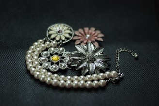 a close up of a necklace with flowers on it