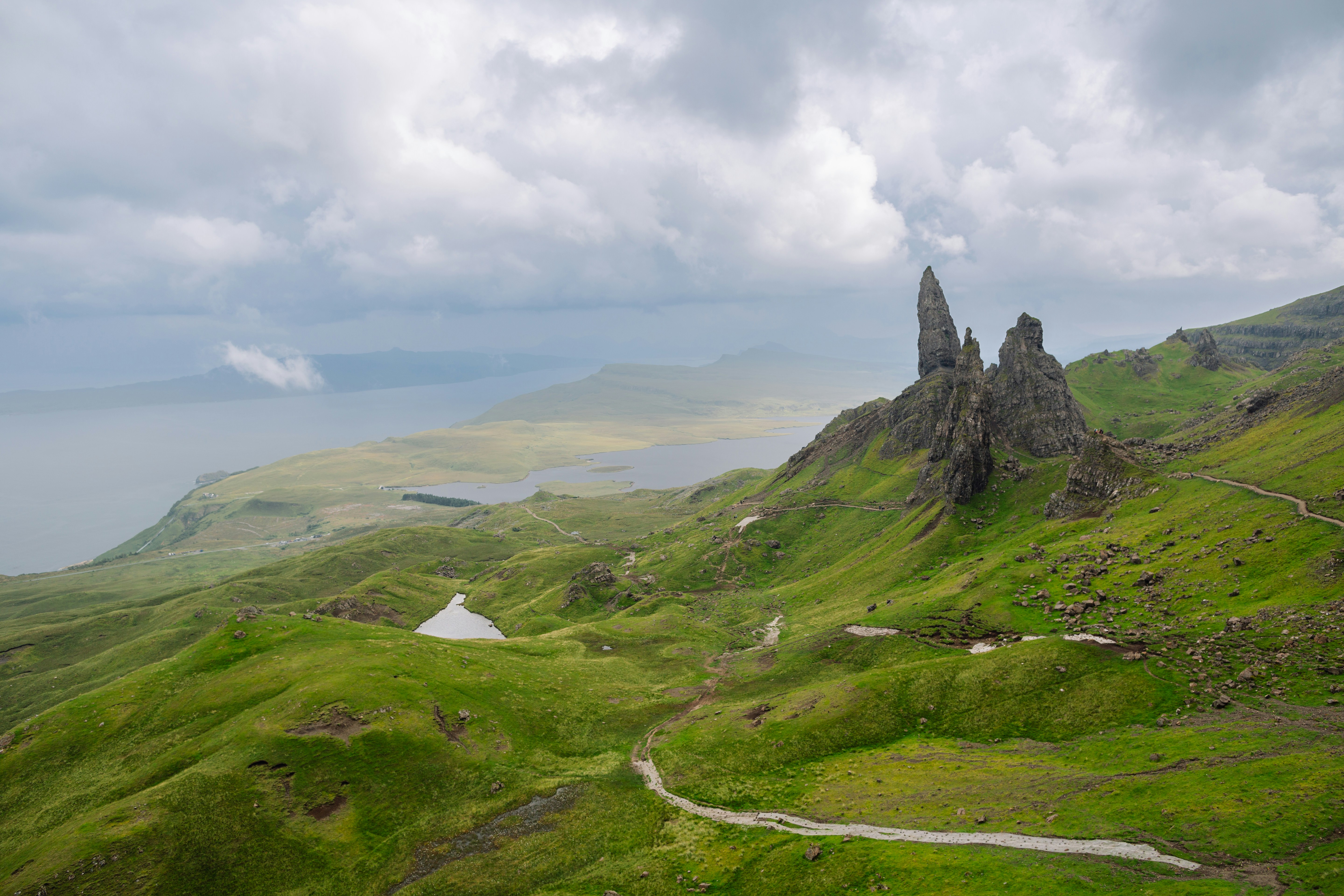 a scenic view of a green mountain with a lake in the distance, 