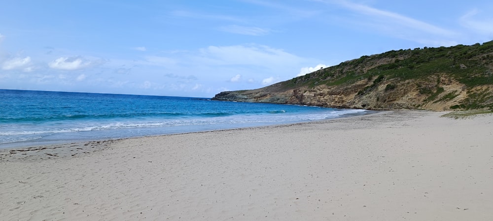 a sandy beach with a hill in the background