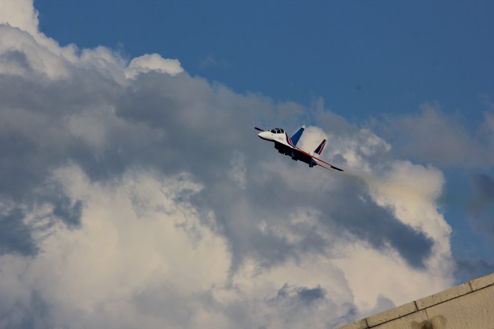 a small airplane flying through a cloudy blue sky