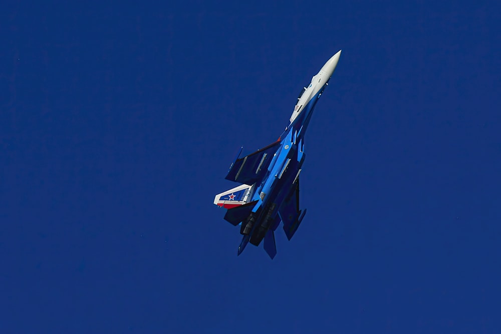 a fighter jet flying through a blue sky