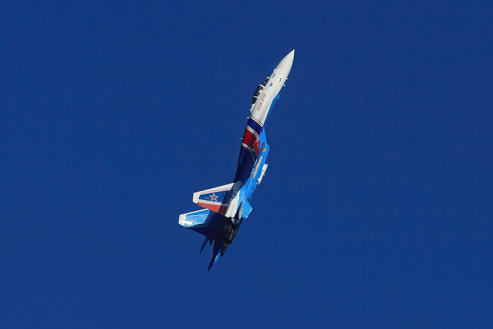 a fighter jet flying through a blue sky