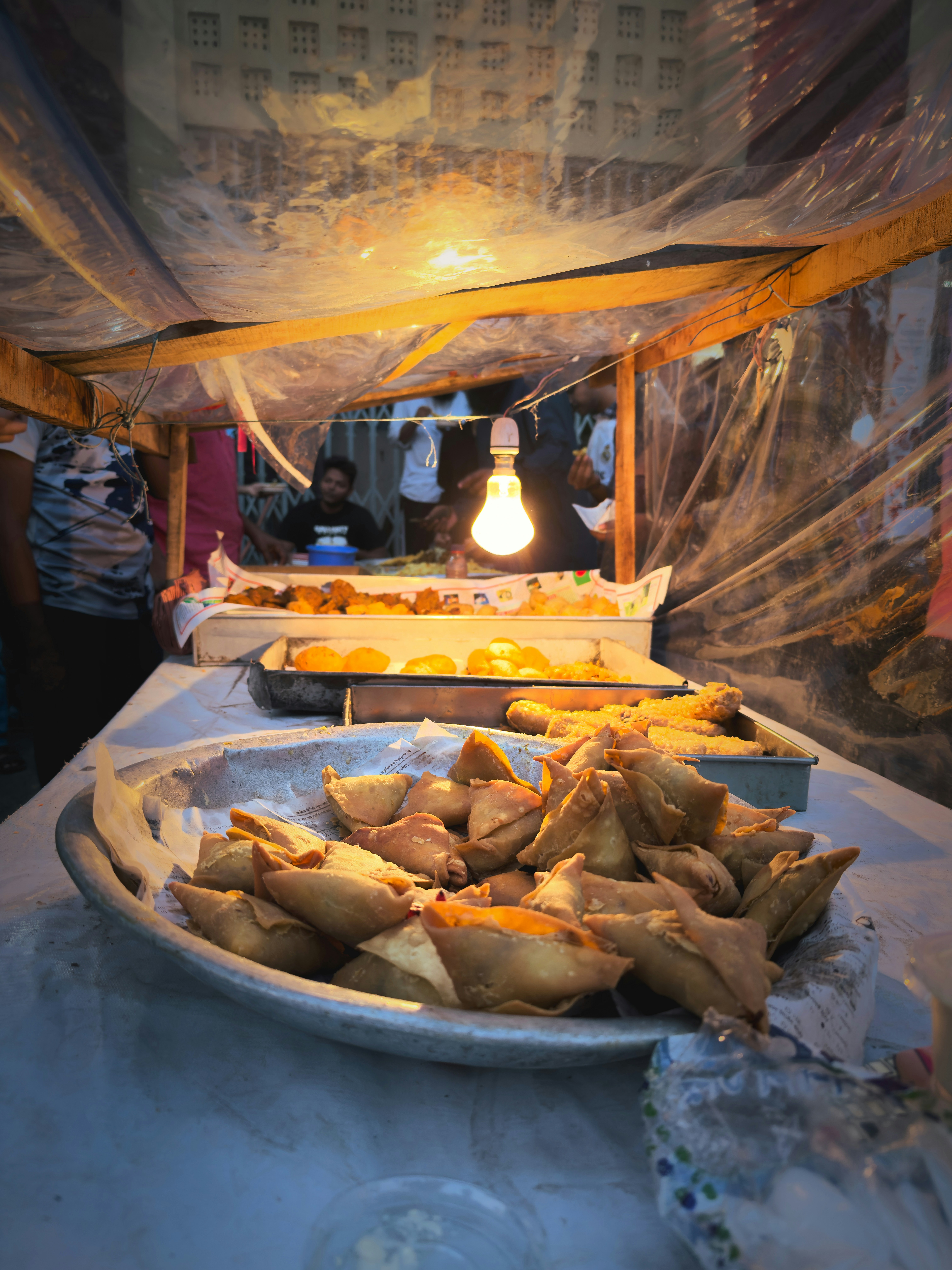 Golden crispy samosas on white plate, warm overhead light, food photography