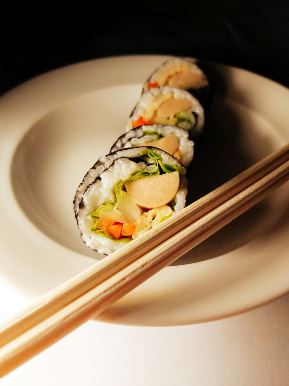 a white plate topped with a sushi and chopsticks