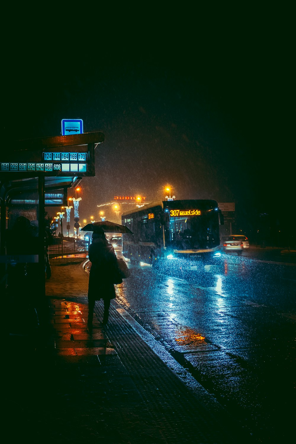 eine Person, die in einer regnerischen Nacht einen Regenschirm hält